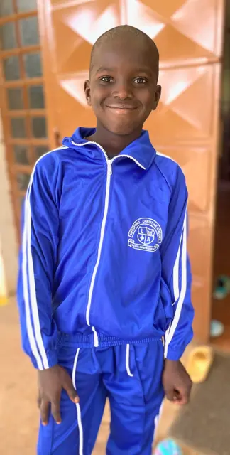 African boy standing with his hand in one pocket proud in his new blue tracksuit uniform