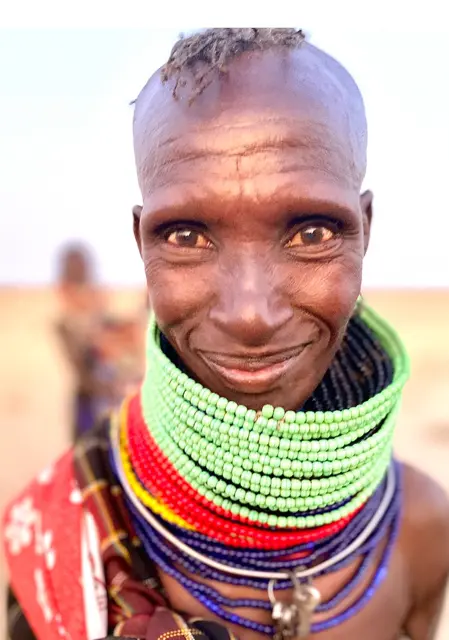 East African Woman with green beaded necklace smiling at the camer